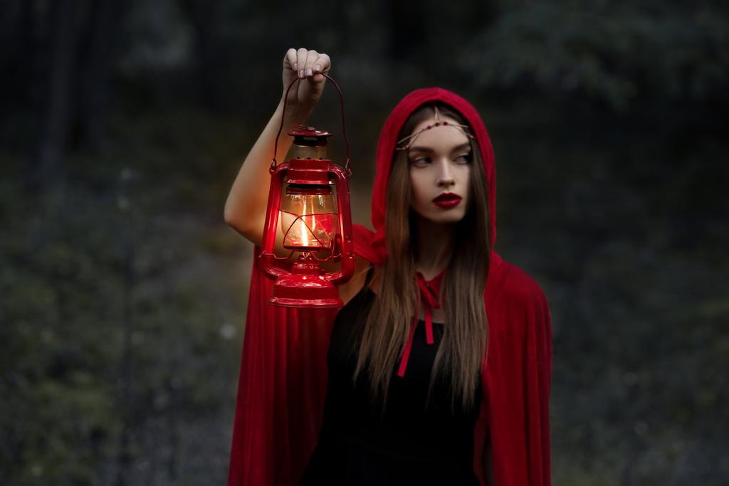 elegante mystic meisje lopen in een donker bos met kerosine lamp - Foto, afbeelding