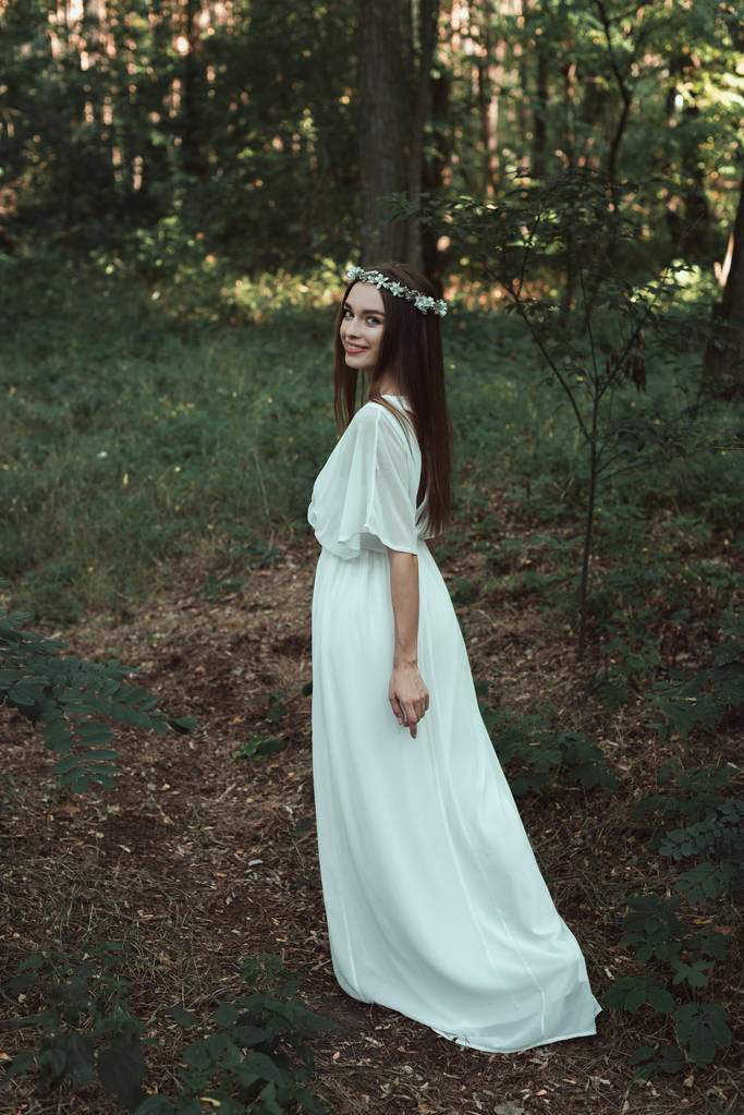 atractiva chica sonriente en vestido blanco caminando en el bosque
 - Foto, imagen