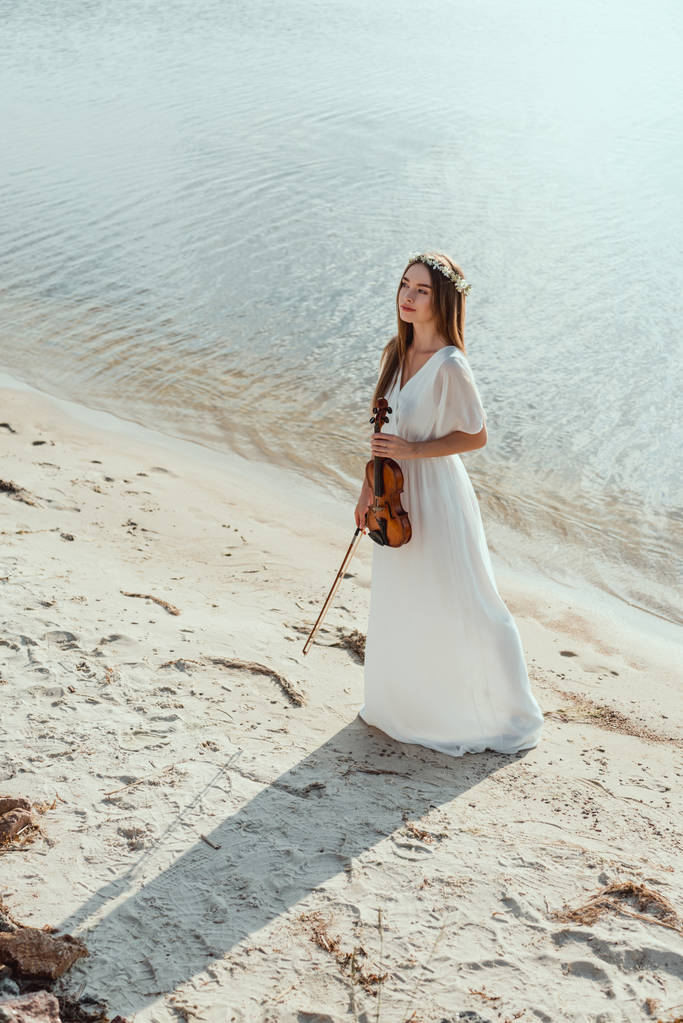 красива дівчина в елегантній сукні тримає скрипку на пляжі
 - Фото, зображення