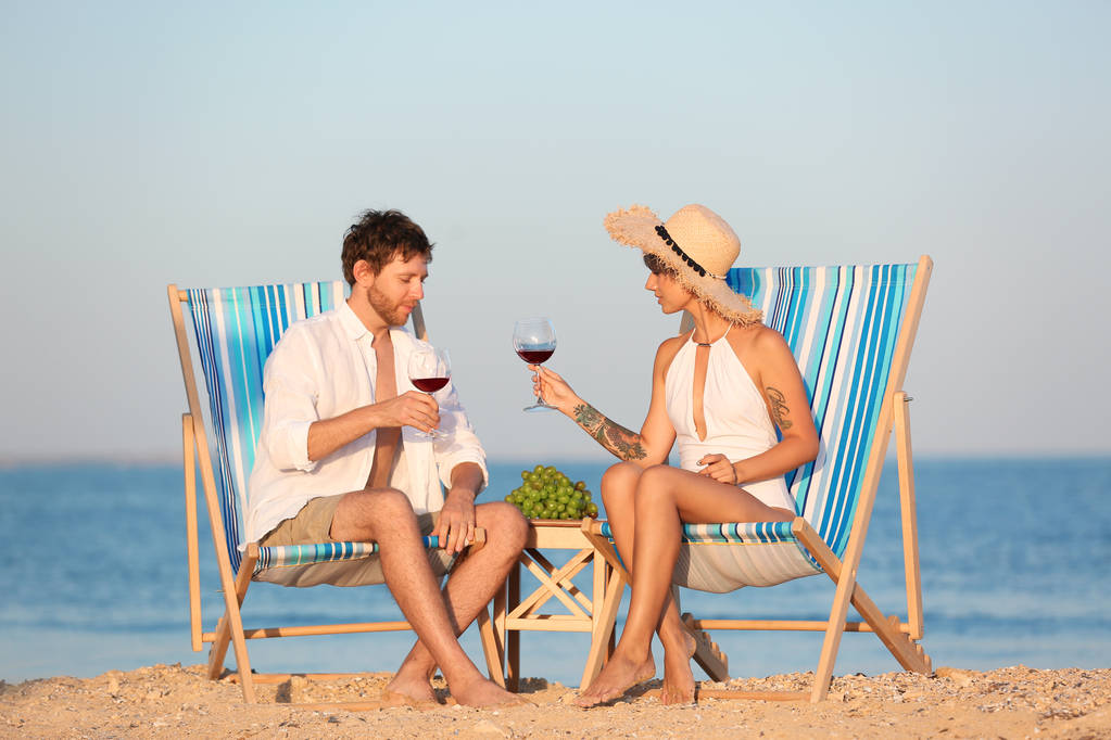 若いカップルがビーチでハンモックでワインのグラスと休憩 - 写真・画像
