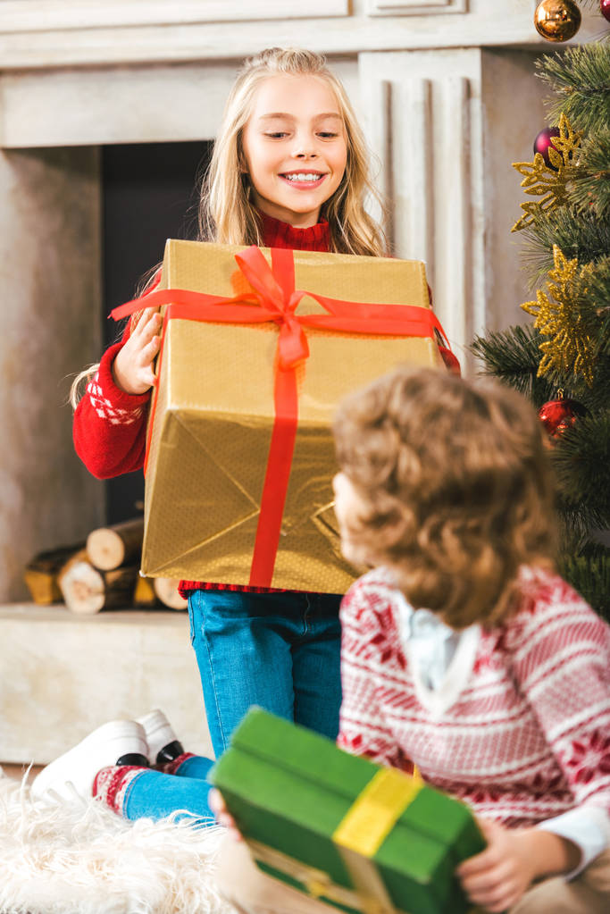 щасливі маленькі брати і сестри з подарунковими коробками святкують Різдво
 - Фото, зображення