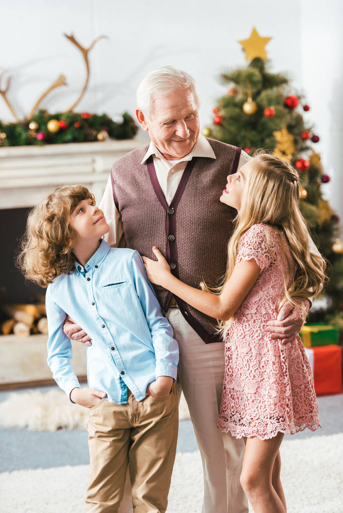 happy grandfather embracing kids in christmas decorated living room at home - Photo, Image