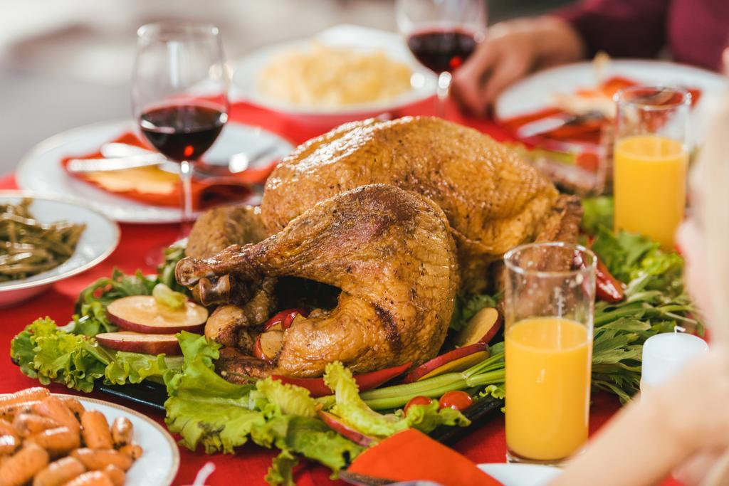 Close-up shot van Turkije op dienblad omgeven met verschillende gerechten op thanksgiving tafel - Foto, afbeelding