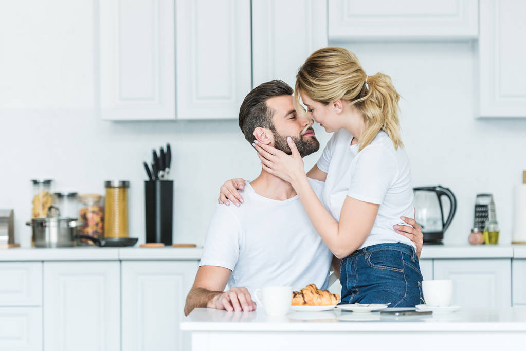 schönes glückliches junges verliebtes Paar küsst sich beim Frühstück in der Küche  - Foto, Bild
