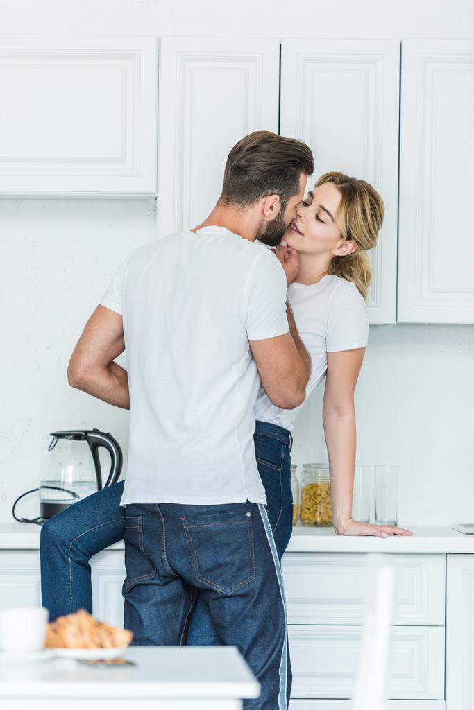 beautiful happy young couple in love kissing at kitchen - Photo, Image