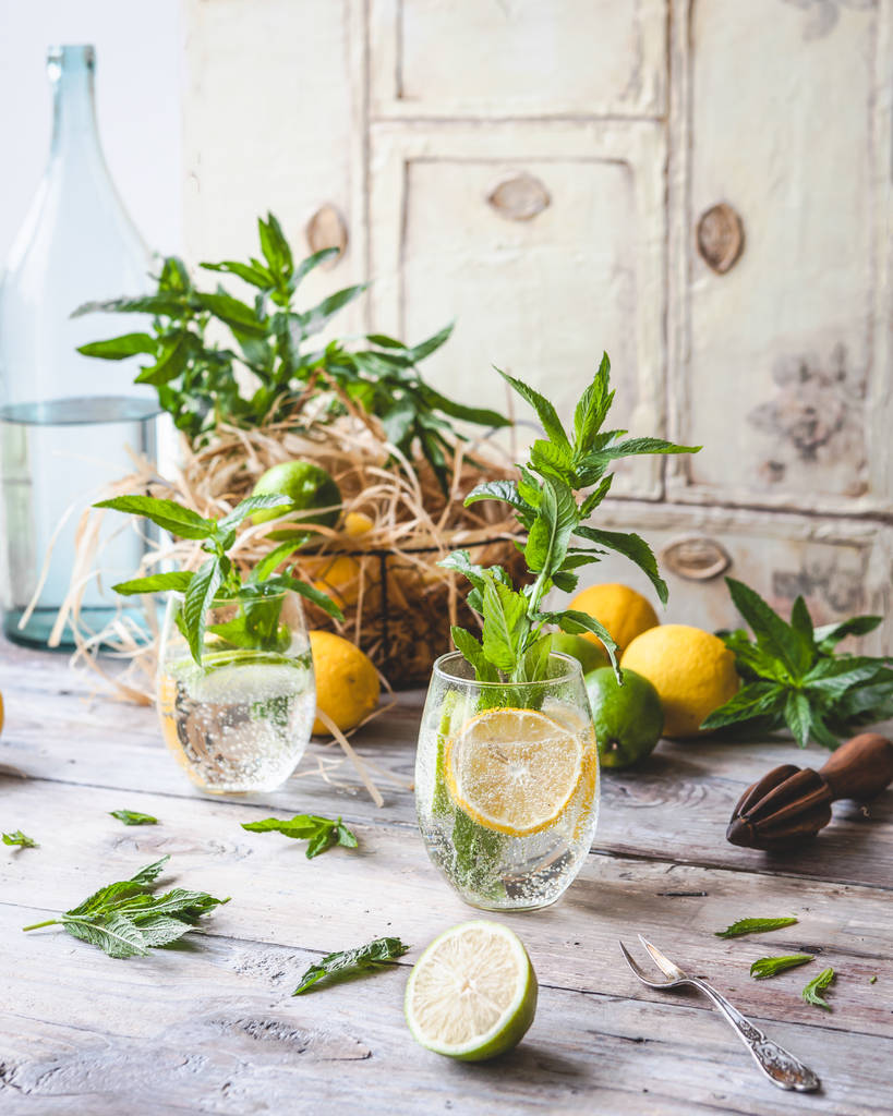 склянки домашнього лимонаду зі скибочками лимона та листя м'яти на старовинному дерев'яному столі
 - Фото, зображення
