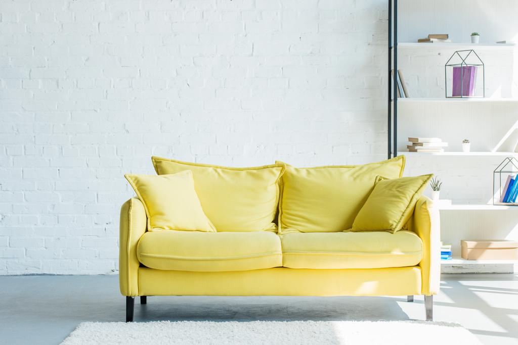 acogedor sofá amarillo con cojines en el interior del salón
 - Foto, imagen