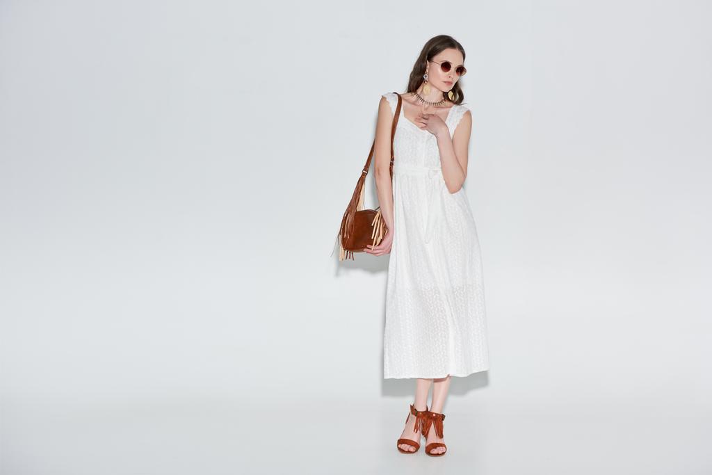 красивая женщина в стильном белом платье и солнечных очках, позирующих на сером
  - Фото, изображение