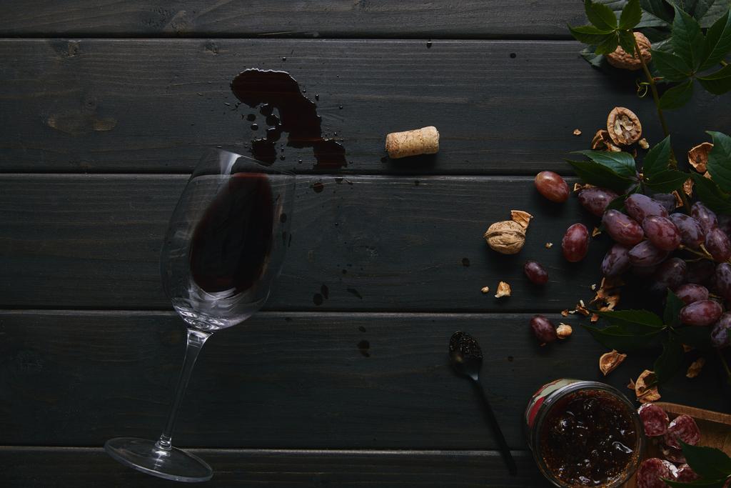 kırmızı şarap, mantar ve fındıklı üzüm cam ahşap yüzey üzerinde yukarıdan  - Fotoğraf, Görsel