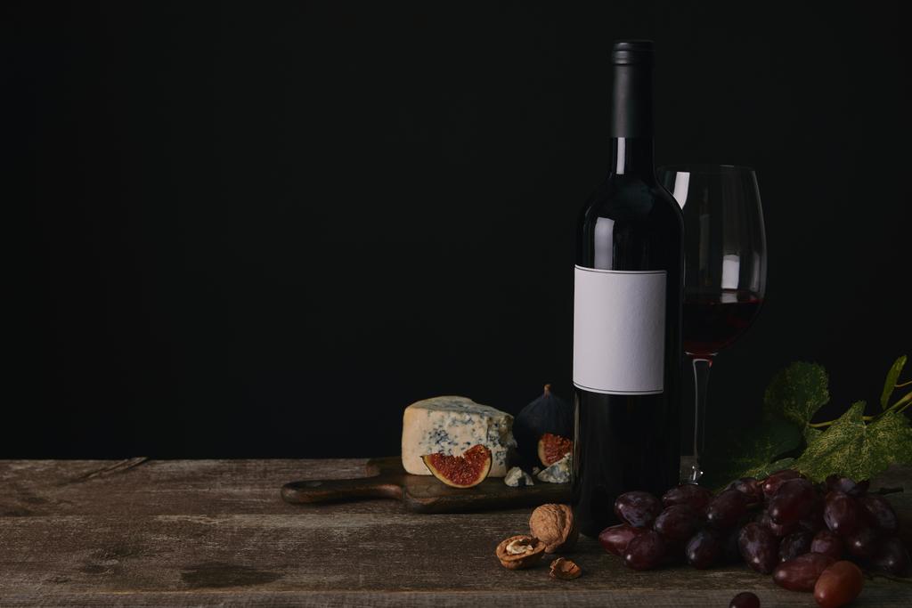 пляшка і келих червоного вина, виноград і сир на дерев'яному столі
 - Фото, зображення