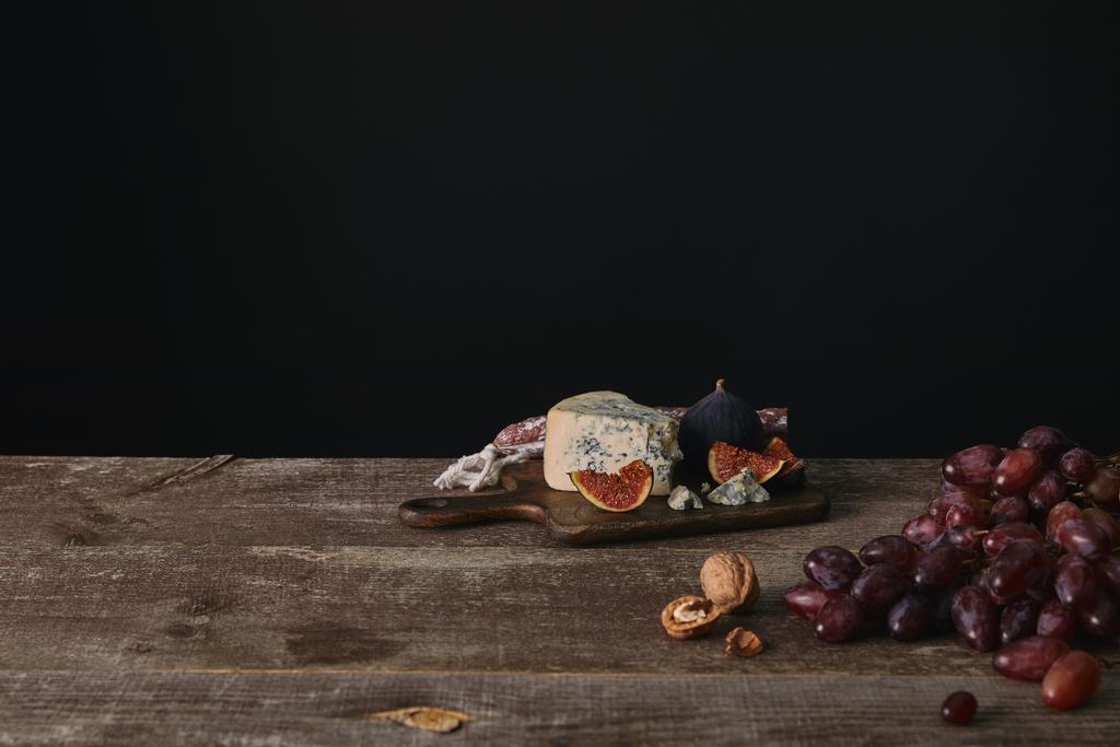 świeżych dojrzałych winogron, orzechy i pysznego sera na drewnianym stole na czarny - Zdjęcie, obraz