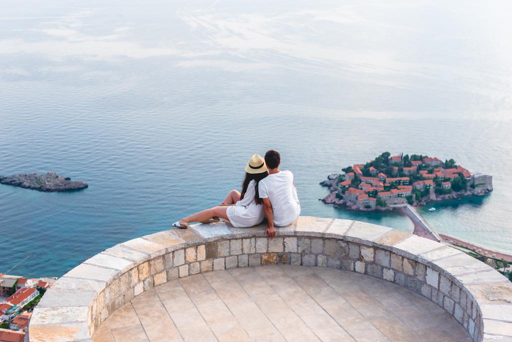 pareja abrazándose en el mirador y mirando la isla de Sveti Stefan en Budva, Montenegro
  - Foto, Imagen