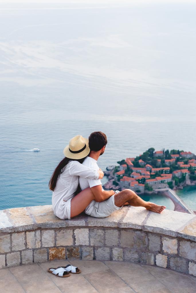 пара обіймати і дивлячись на острові міста Свєті-Стефан в Адріатичному морі, Будва, Чорногорія  - Фото, зображення
