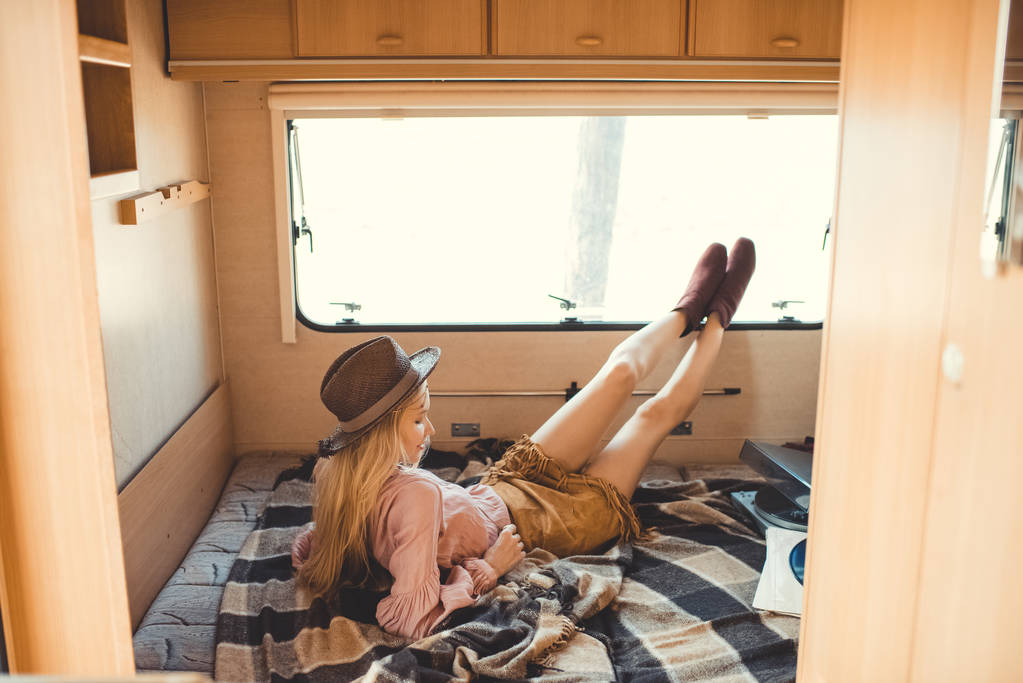 hippie dziewczyna w kapeluszu odpoczynku wewnątrz camper van z winylu gracza i rekordy - Zdjęcie, obraz