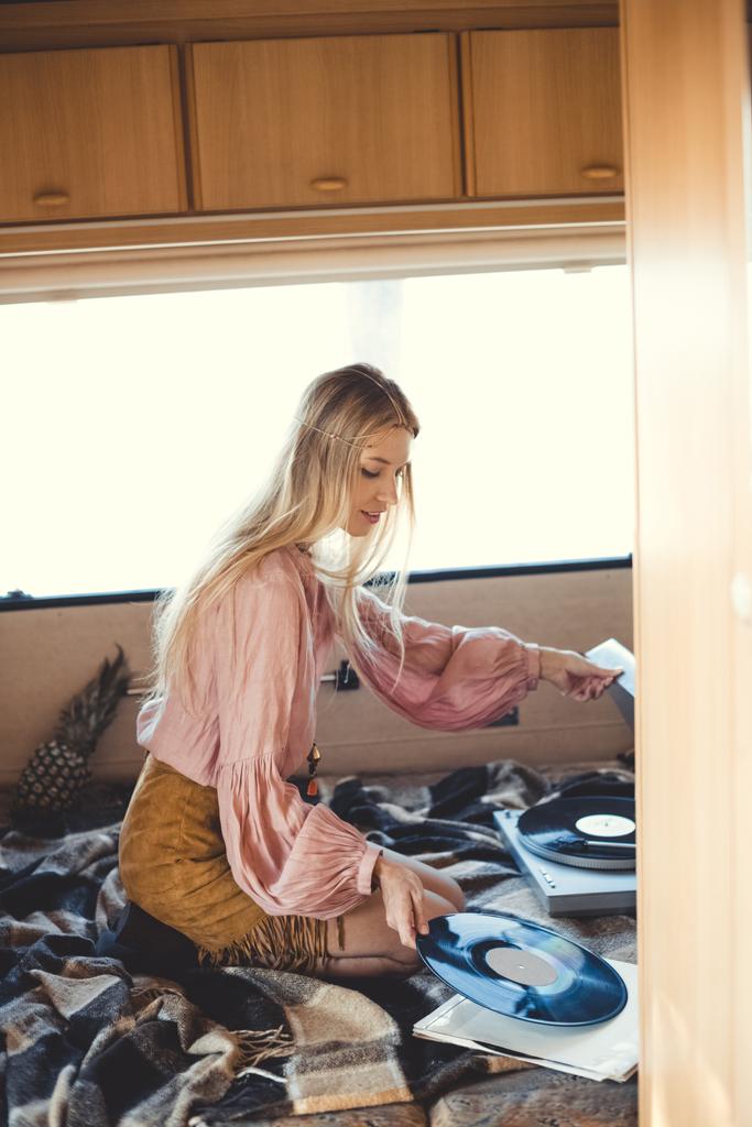 mooie hippie meisje vinyl record ingebruikneming speler binnen kampeerauto - Foto, afbeelding