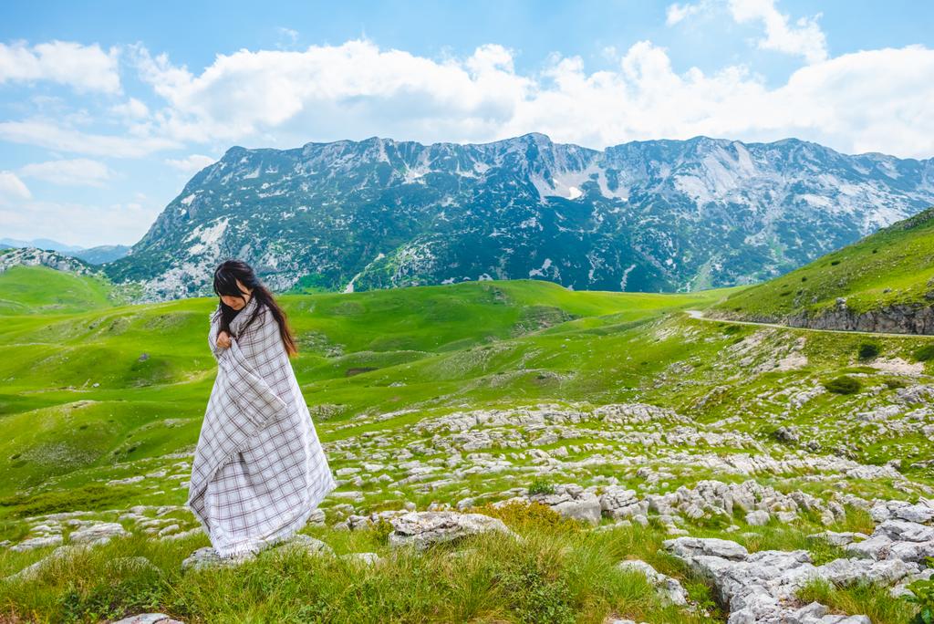 beautiful woman standing wrapped in blanket on valley in Durmitor massif, Montenegro - Photo, Image