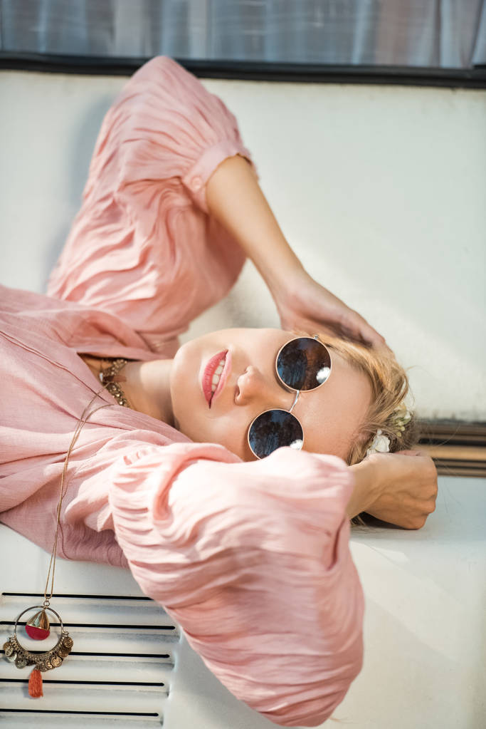 attractive hippie girl in sunglasses lying on camper van - Photo, Image