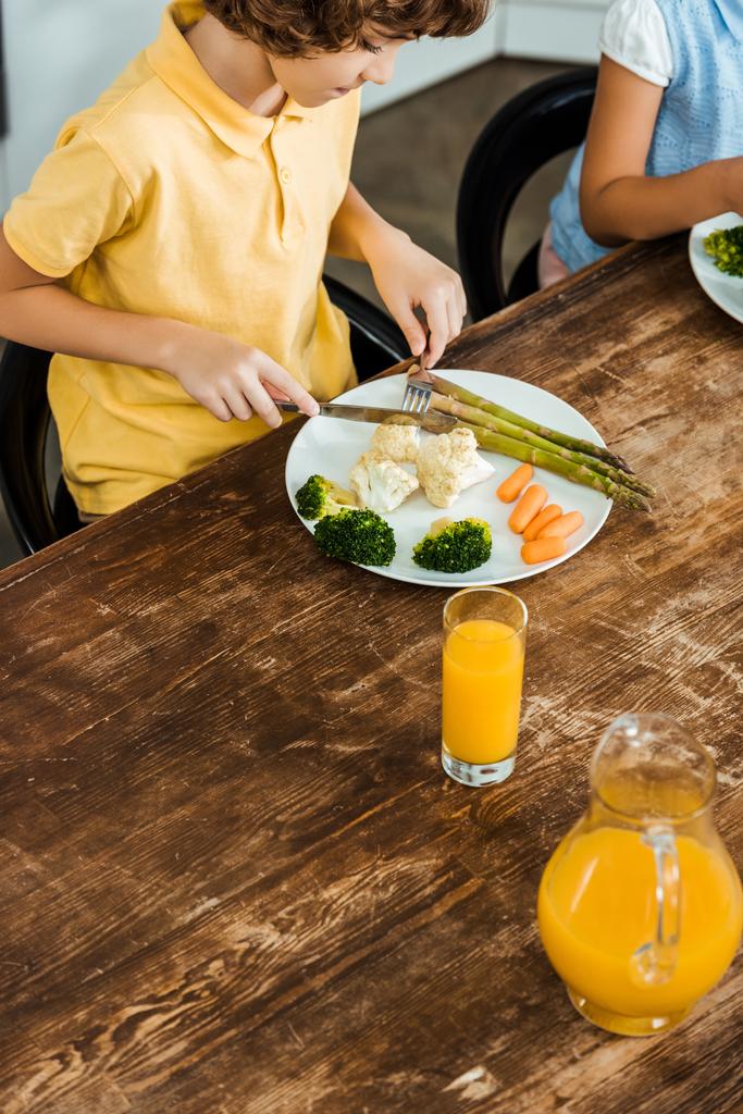 vista ad alto angolo di forchetta per bambini con coltello e mangiare verdure sane
 - Foto, immagini
