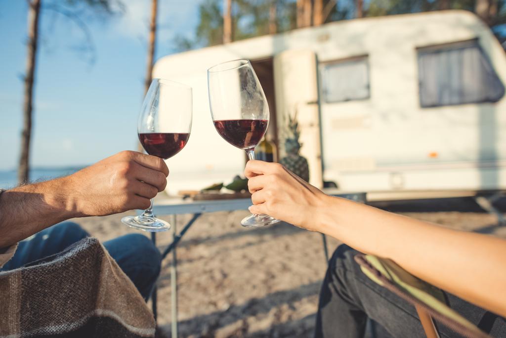 キャンプでピクニック中にワインのガラスをチリンとカップルのビューをトリミング - 写真・画像