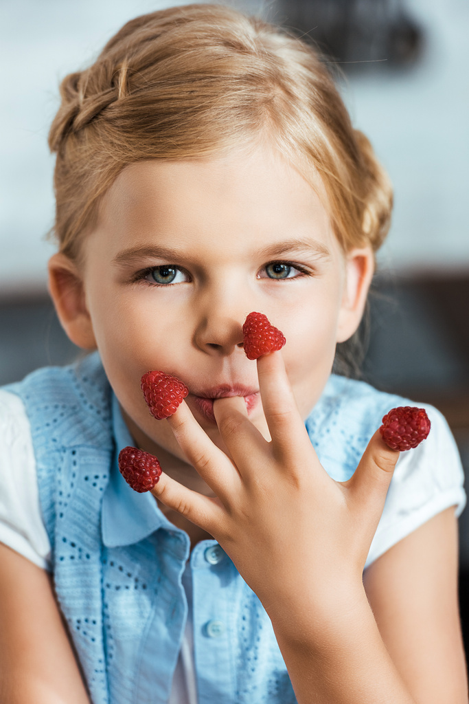 criança adorável comendo framboesas e olhando para a câmera
 - Foto, Imagem