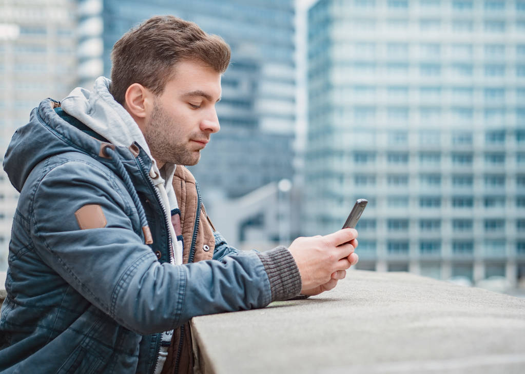 Profil oder Seitenansicht des Typen mit Telefon. Mann mit Smartphone, im Freien - draußen - Foto, Bild