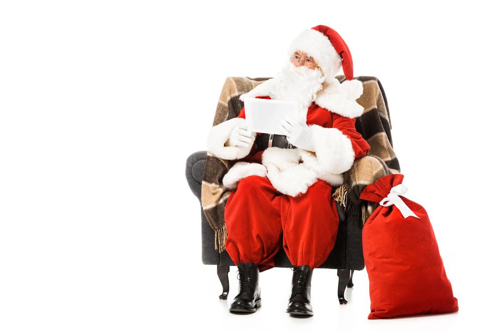 Санта-Клаус сидит в кресле с табличкой и смотрит далеко изолированы на белом
 - Фото, изображение