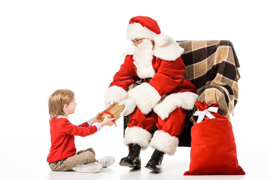 Père Noël présente cadeau de Noël à l'enfant assis dans un fauteuil isolé sur blanc
 - Photo, image