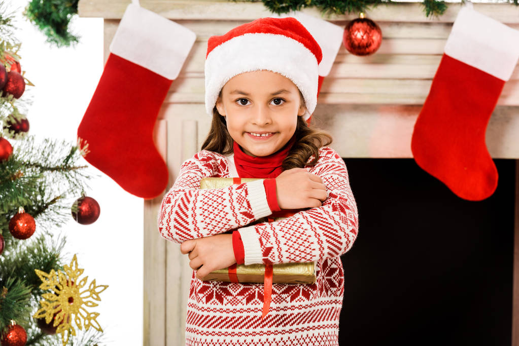 χαμογελαστό μικρό παιδί κρατώντας χριστουγεννιάτικο δώρο και βλέπουν τα φωτογραφικών μηχανών - Φωτογραφία, εικόνα