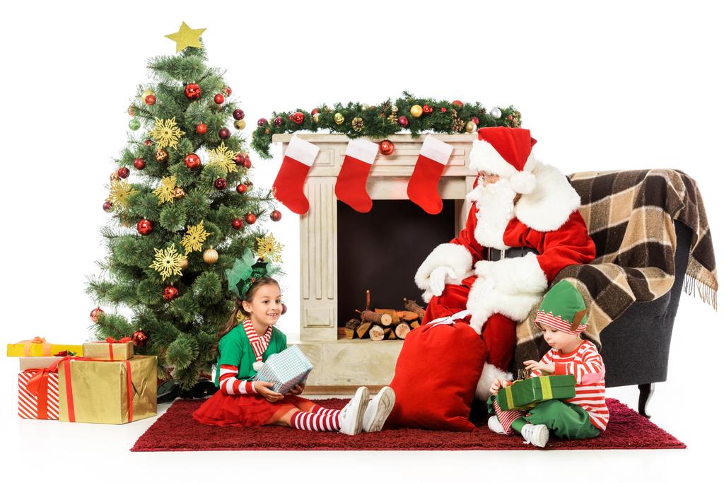 happy kids and santa sitting in front of fireplace together isolated on white - Photo, Image
