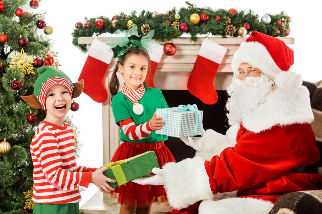 happy kids taking christmas gifts from santa claus isolated on white - Photo, Image
