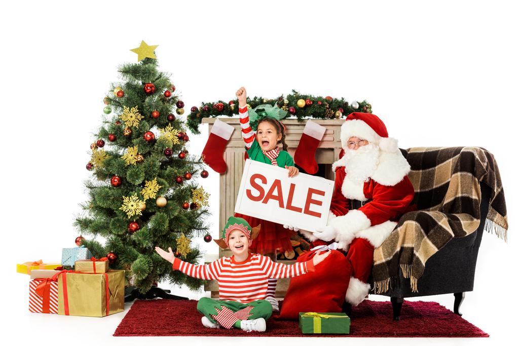 ευτυχής παιδιά στα κοστούμια elf και santa κρατώντας πανό "πώληση", χριστουγεννιάτικα ψώνια - Φωτογραφία, εικόνα