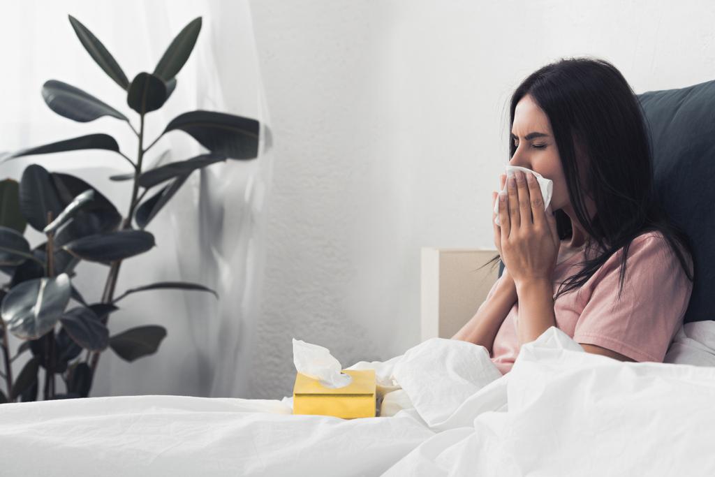 malade jeune femme avec boîte de serviettes en papier assis dans le lit
 - Photo, image