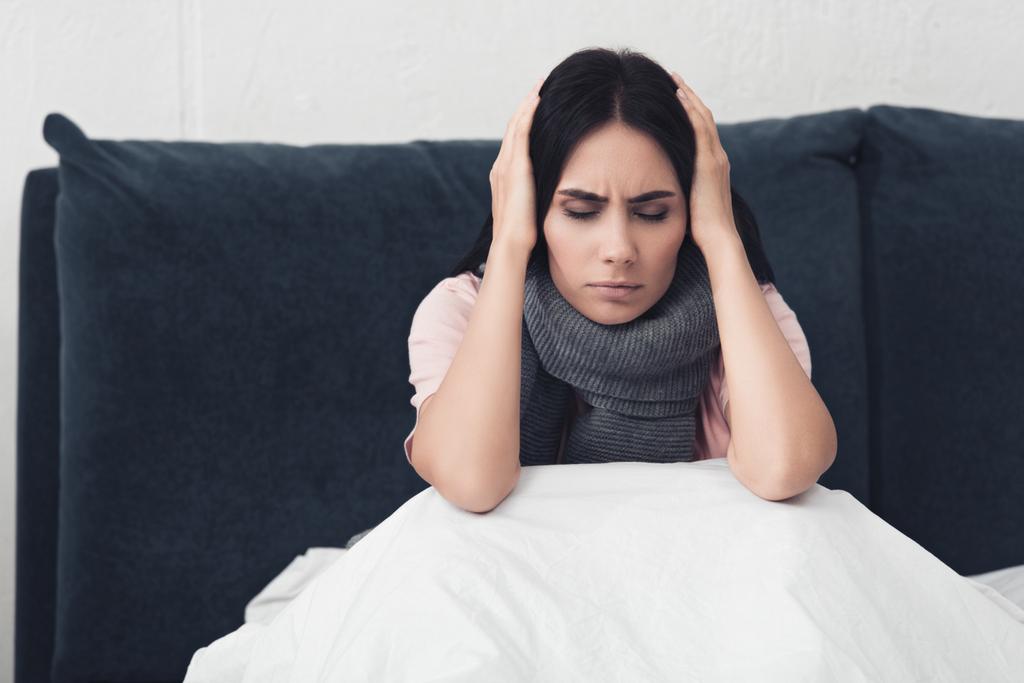 jeune femme malade assise au lit et tenant la tête pendant les maux de tête
 - Photo, image