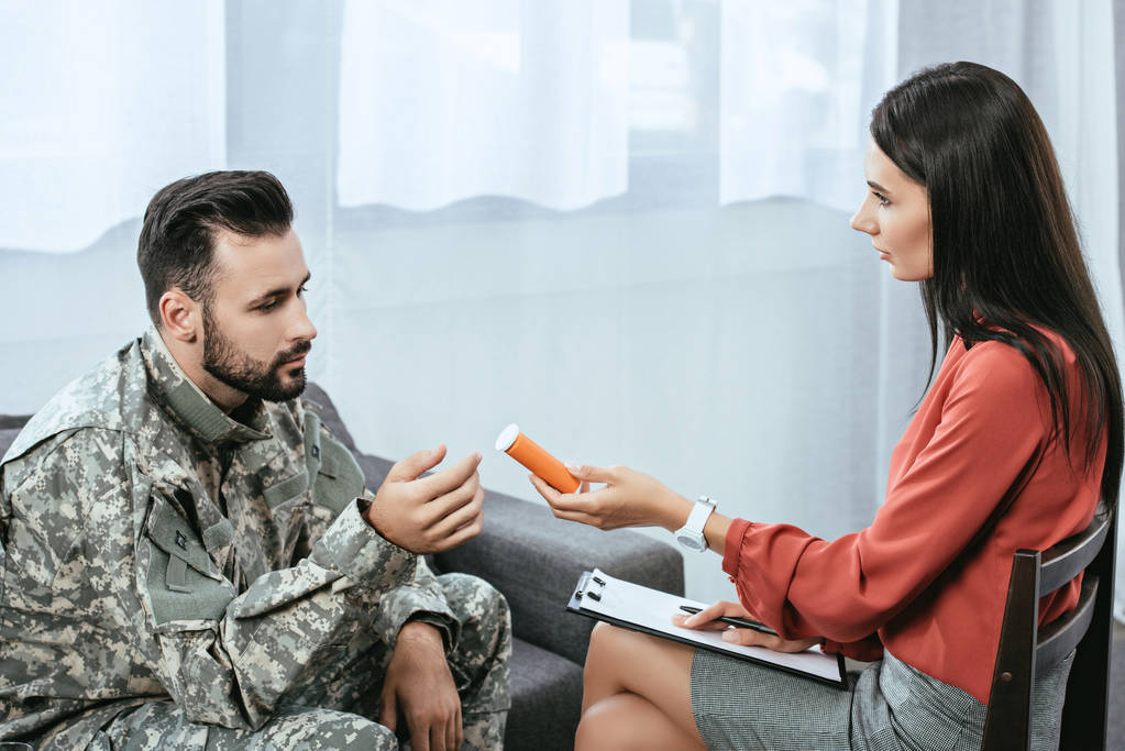 psiquiatra dando contenedor de pastillas al soldado durante la sesión de terapia
 - Foto, Imagen