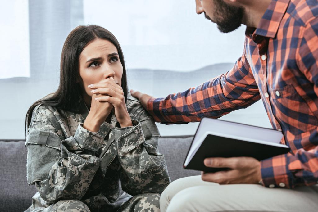 обрезанный снимок психиатра, поддерживающего плачущую женщину-солдата во время терапии
 - Фото, изображение