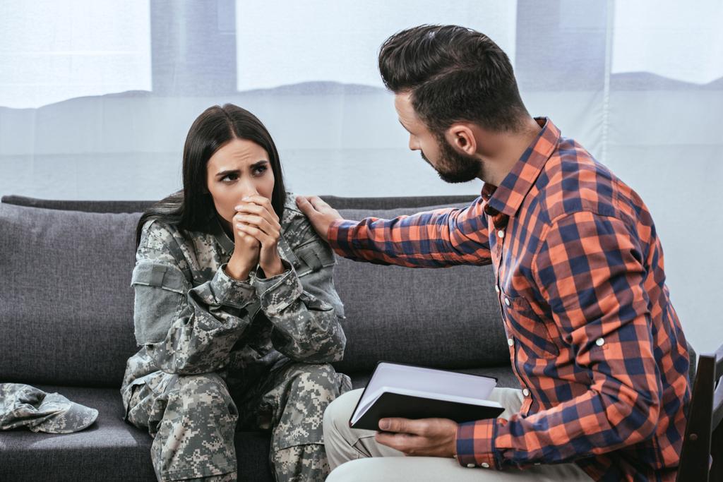 психиатр поддерживает плачущую женщину-солдата во время сеанса терапии
 - Фото, изображение