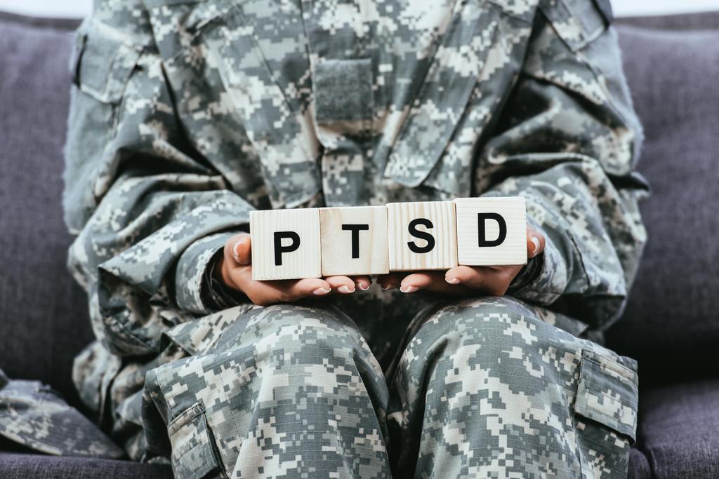 Армійське обмундирування, сидячи на дивані і проведення Двоярусне з ПТСР знак обрізану постріл жінка-солдат - Фото, зображення