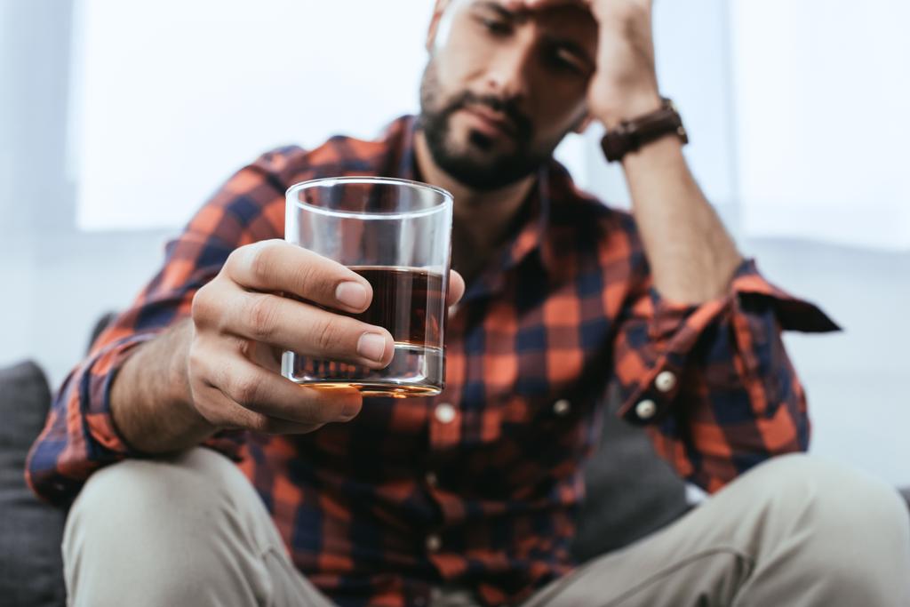 zbliżenie z przygnębiony młody człowiek z szklanką whisky - Zdjęcie, obraz