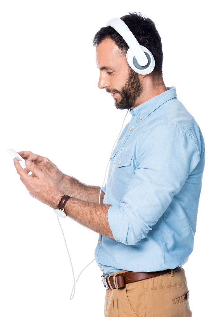 音楽を聴くと、白で隔離のスマート フォンを使用してひげを生やした男の側面図 - 写真・画像