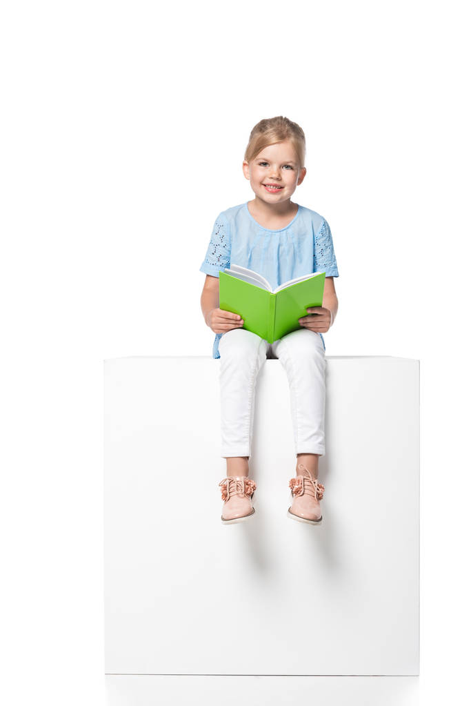 дитина з книгою, що сидить на білому кубі ізольована на білому
 - Фото, зображення