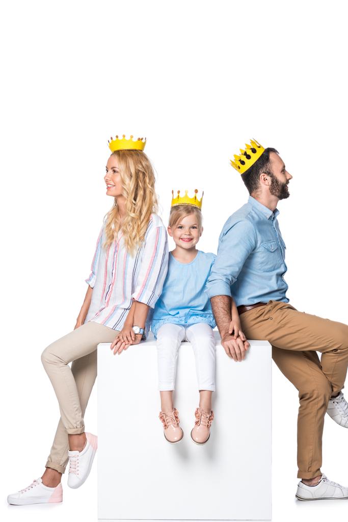 family with yellow cardboard crowns sitting on white cube isolated on white - Photo, Image