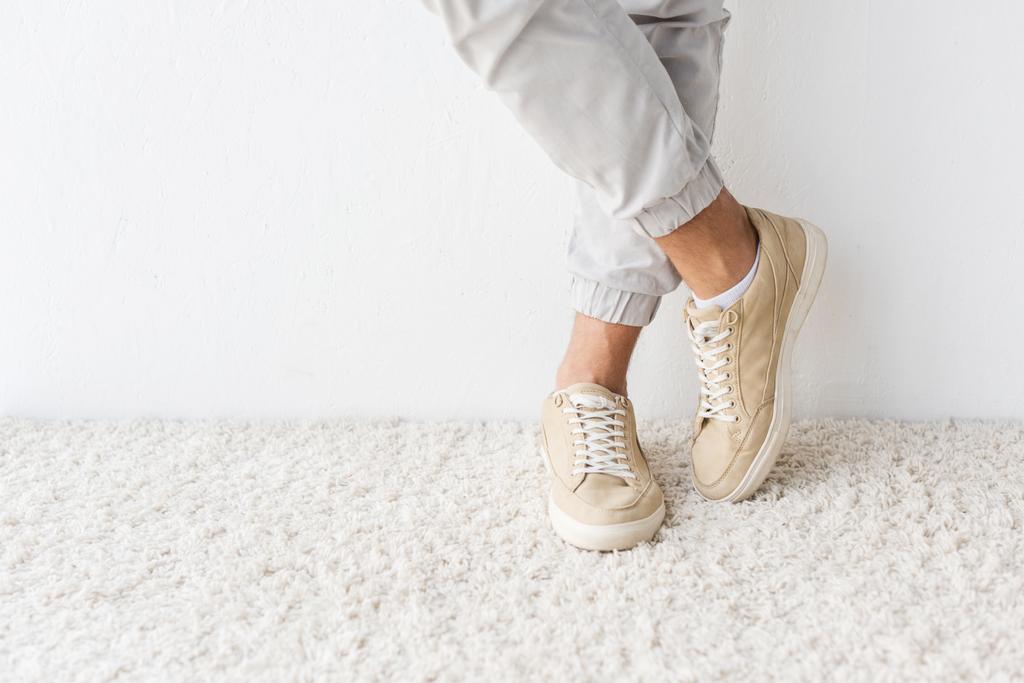 cropped view of casual man standing on beige rug  - Photo, Image