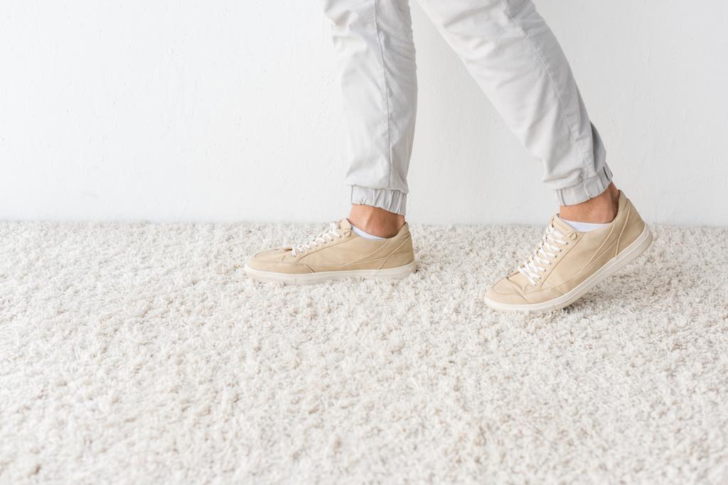 oříznutý pohled mužských nohou o koberec proti bílé zdi - Fotografie, Obrázek