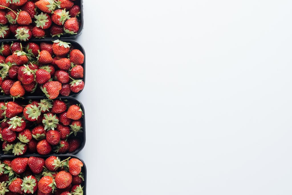 vista superior de la fila de recipientes con fresas maduras en la mesa blanca con espacio de copia en blanco
 - Foto, imagen