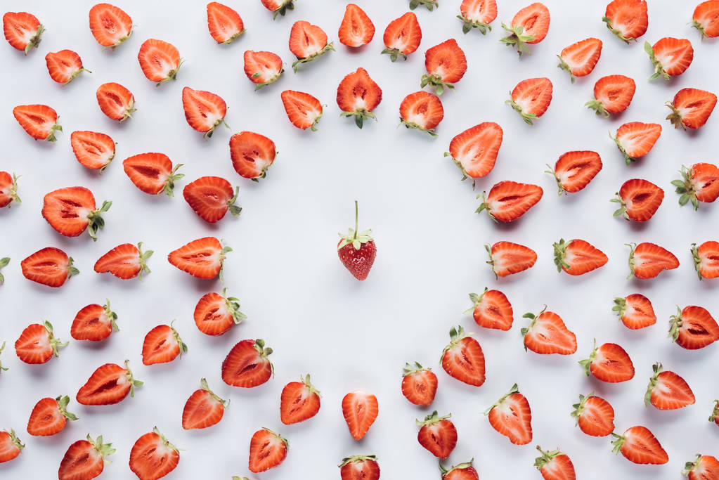 Rundrahmen halbierter reifer Erdbeeren mit Ganzem in der Mitte auf weißer Oberfläche - Foto, Bild