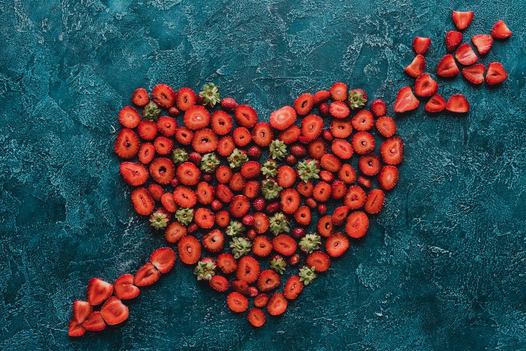 ylhäältä näkymä sydämen lävistetty nuolimerkki mansikoita sinisellä betonipinnalla
 - Valokuva, kuva