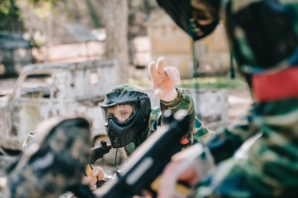 mužské paintball hráč v maskovací uniforma zbraň značky ukazující prsty do svého týmu venku - Fotografie, Obrázek