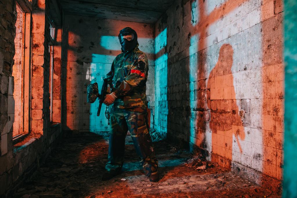 fiducioso giocatore di paintball maschile in maschera e camuffamento tenendo pistola paintball in edificio abbandonato
 - Foto, immagini