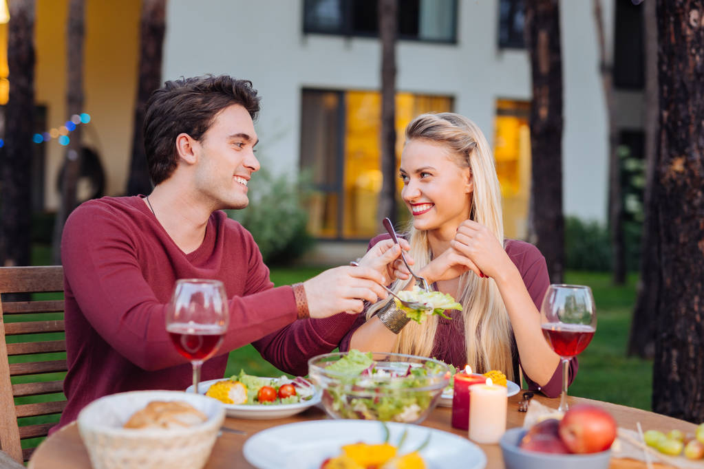 Iloinen positiivinen mies jakaa salaatin tyttöystävänsä kanssa
 - Valokuva, kuva