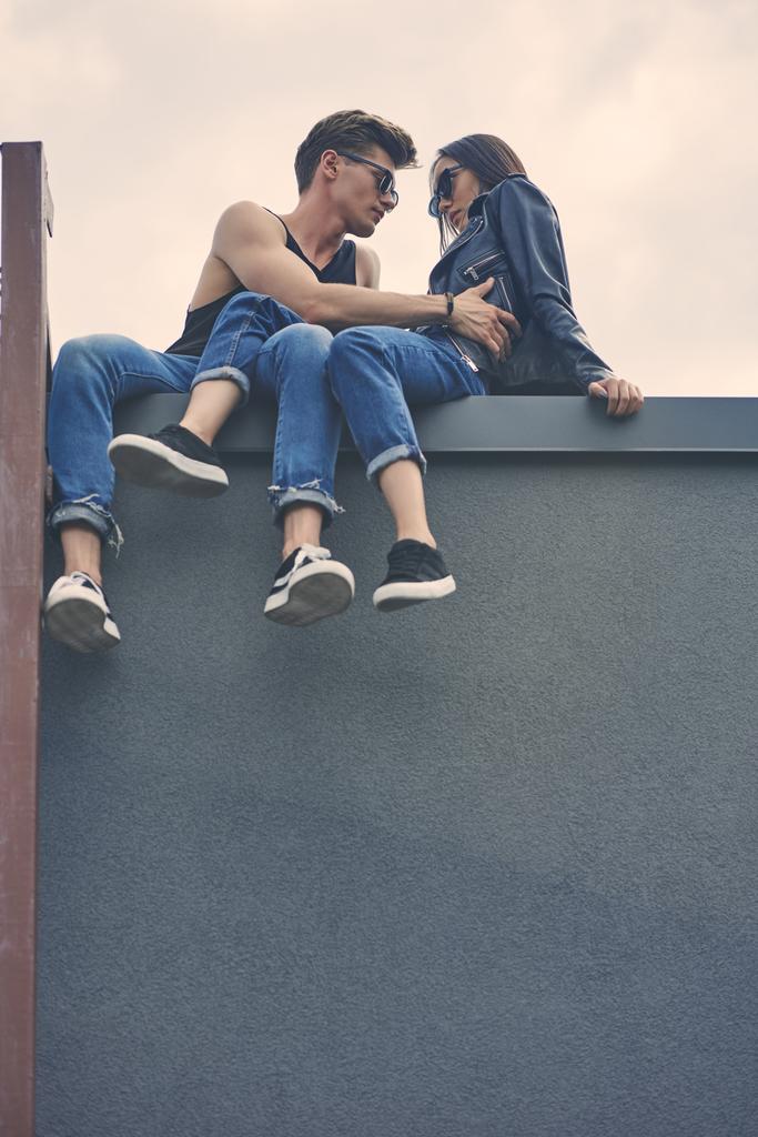 Onderaanzicht van stijlvolle Sex tussen verschillendre rassen paar flirten en knuffelen op dak - Foto, afbeelding
